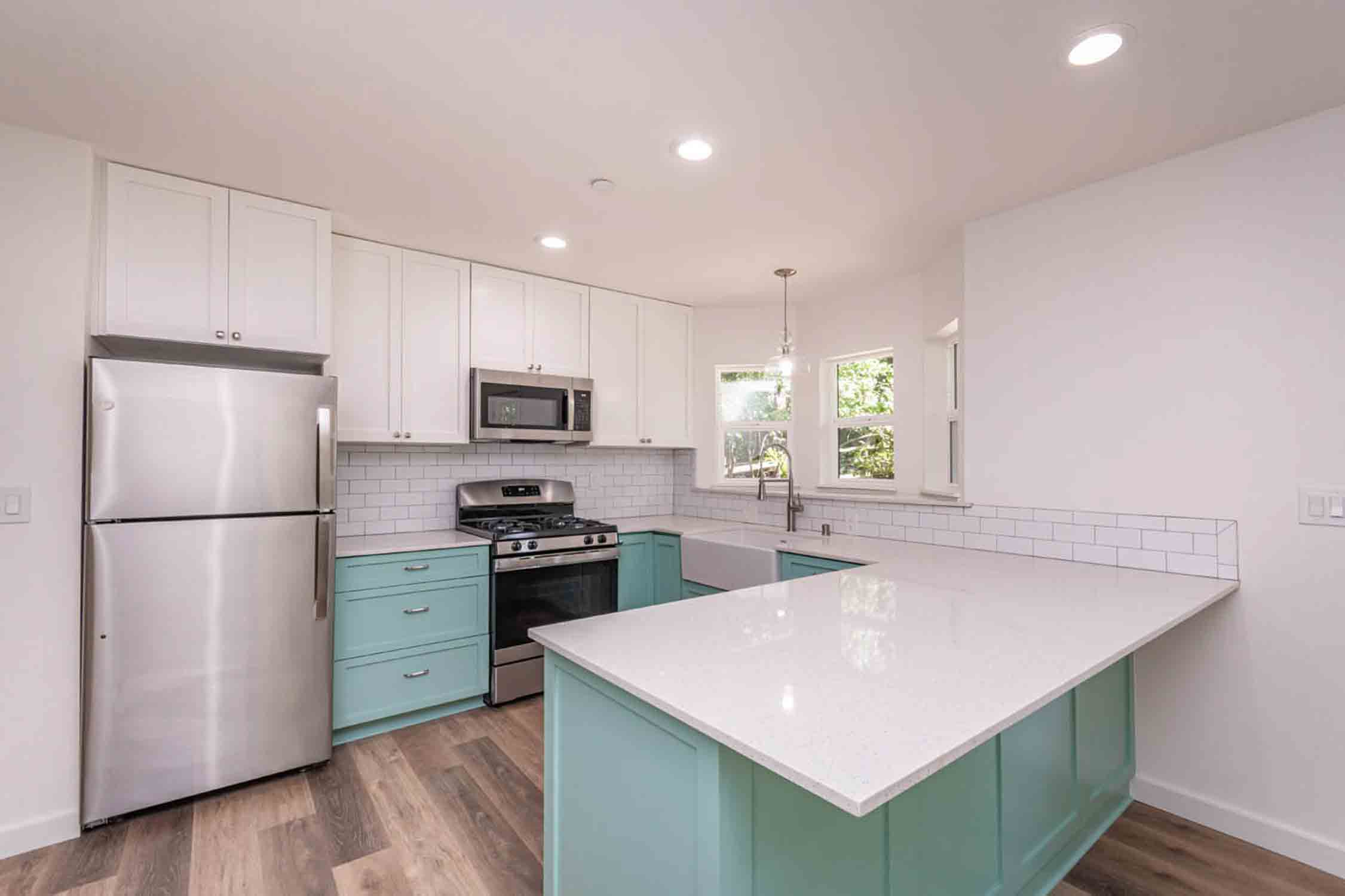 A beautiful white kitchen with green countertops in an ADU home, contact our top tiny home builders in Salt Lake City.