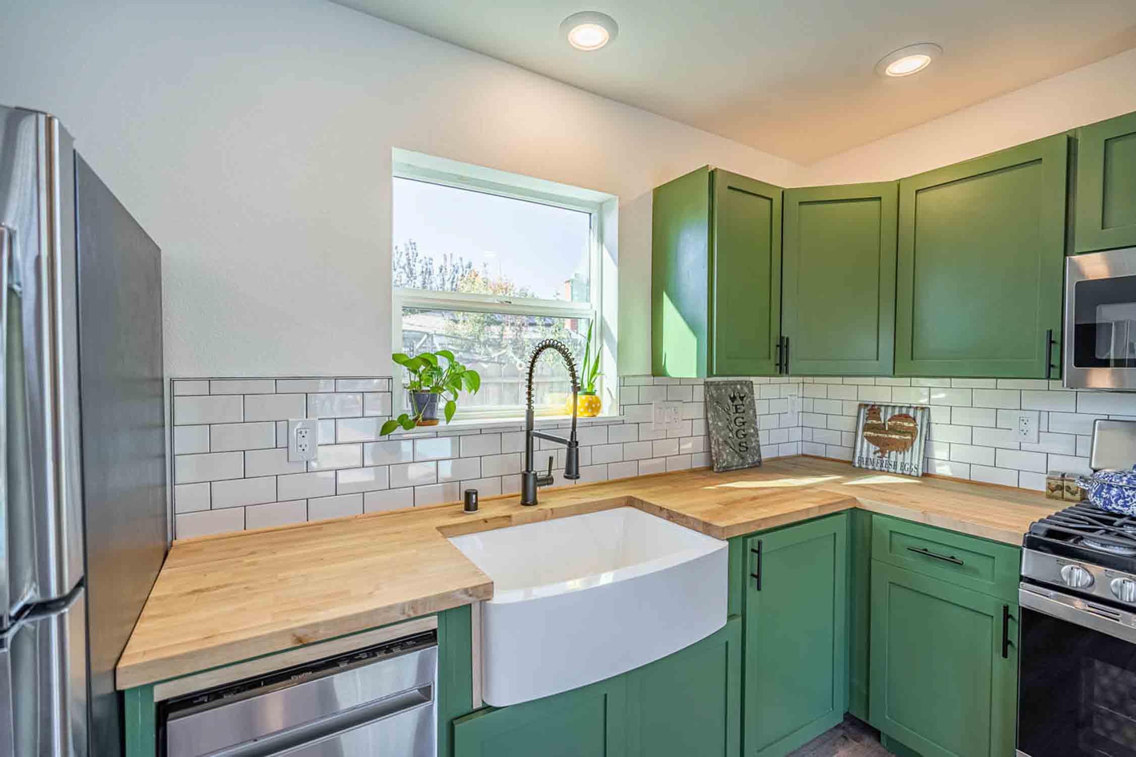 A Anchored Tiny Homes modern tiny home with a dark green kitchen, provided by our Salt Lake City guest house builder.