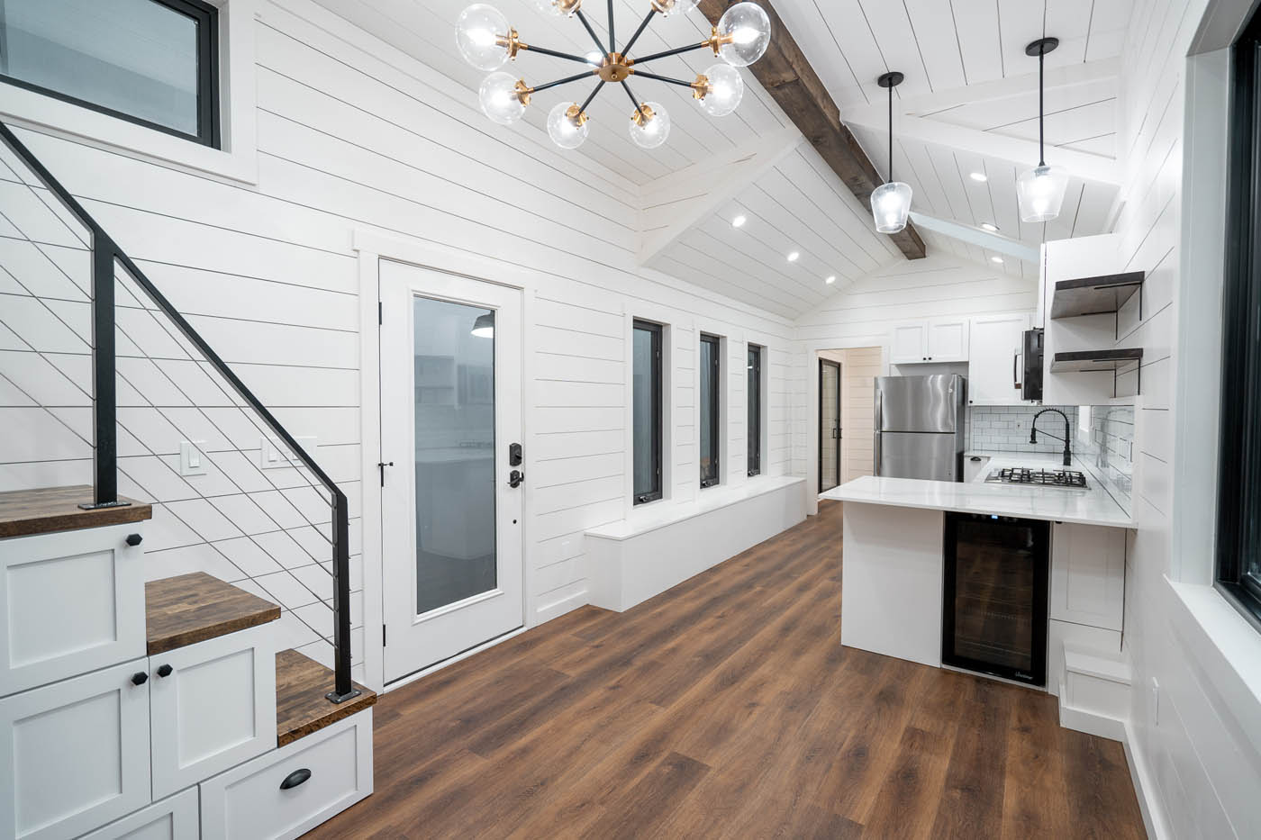 A modern home with dark floors and white kitchen cabinets, provided by one of the best Simpsonville / Laurens tiny house companies.